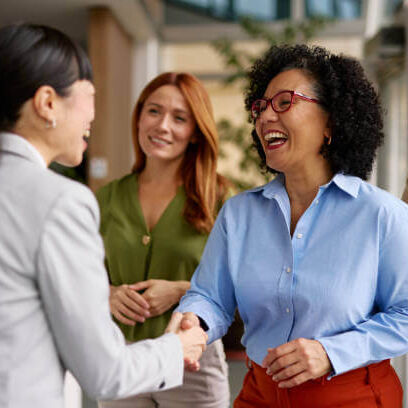 A group of diverse business colleagues engaged in a friendly handshake in a modern office setting, symbolizing partnership and cooperation. The atmosphere is positive and professional.